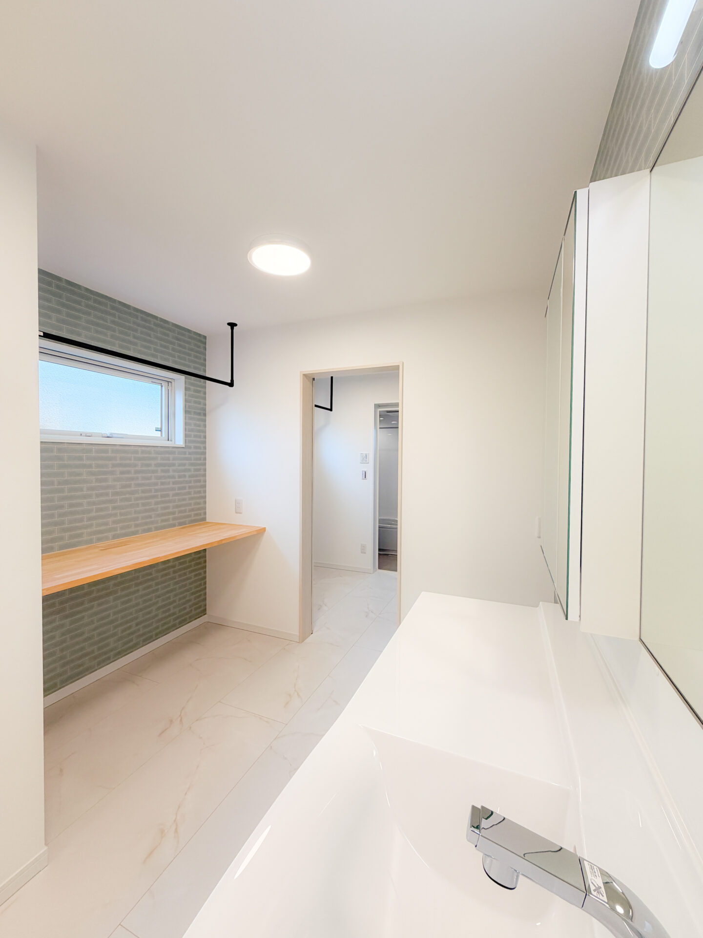 カウンターとハンガーパイプを備えた家事効率の良いランドリールーム